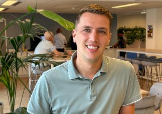 Collega Mark staat aan een hoge tafel in de koffieruimte